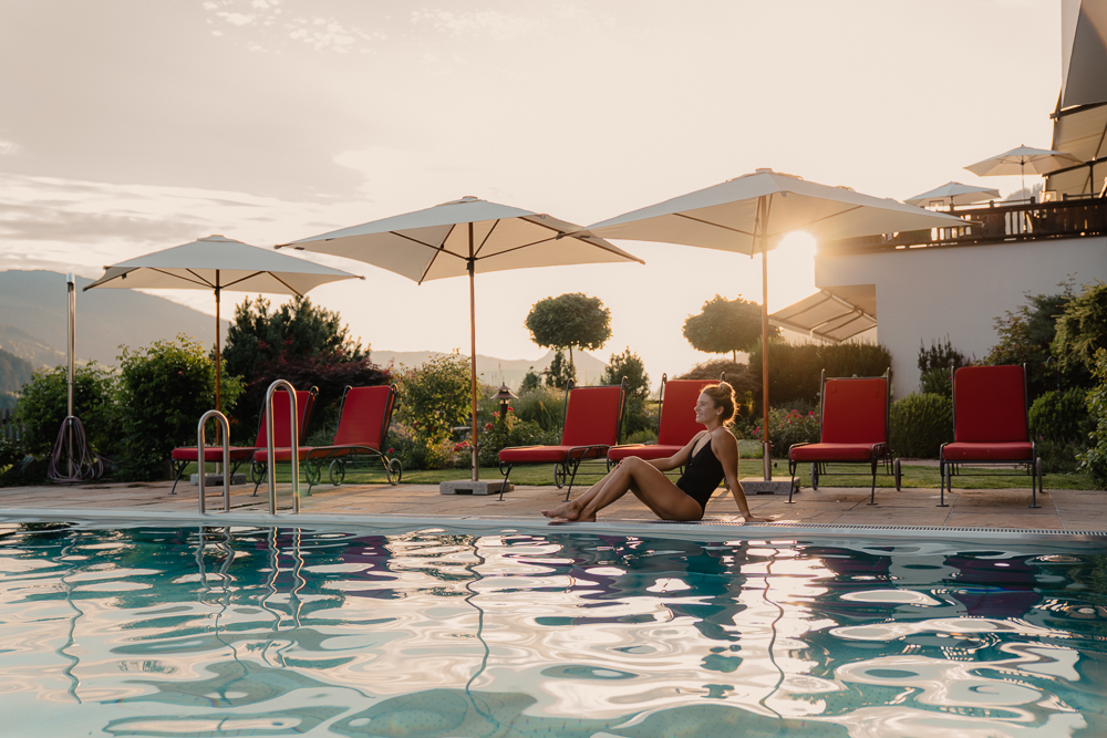 Luxusurlaub - Tirol - Frau am Pool Abenstimmung - Alpbacherhof****s - Mountain & Spa Resort