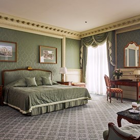 Luxushotel: Die Suiten sind luxuriös ausgestattet und bieten eine gemütliche Couch-Ecke und einen Schlafbereich mit Doppelbett oder 2 Einzelbetten. Die Dekoration, in sanftem Grün gehalten, trägt zu einer sehr ruhigen, entspannten Atmosphäre bei. - Grand Hotel Wien