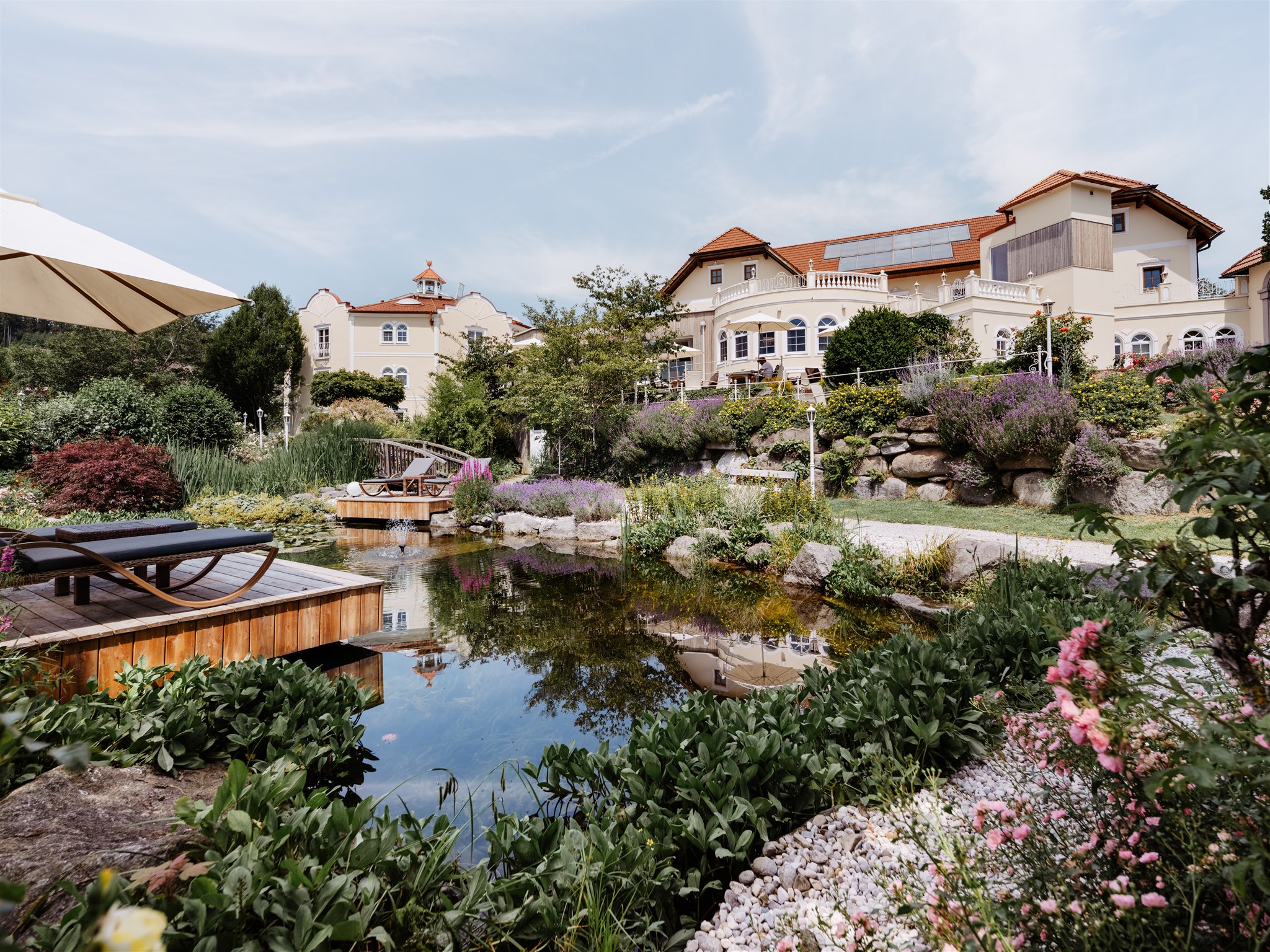 Luxusurlaub - Oberösterreich - Frontansicht Hotel BERGERGUT mit Terrasse und Seerosenteich - Genießerhotel Bergergut ****s
