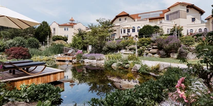 Luxusurlaub - Restaurant: Gourmetrestaurant - Oberösterreich - Frontansicht Hotel BERGERGUT mit Terrasse und Seerosenteich - Genießerhotel Bergergut ****s