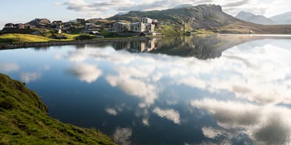 Luxusurlaub - Parkplatz: gebührenpflichtig in Gehweite - frutt Lodge & Spa sowie Family Lodge mit Melchsee im Vordergrund, Sommer - Frutt Mountain Resort