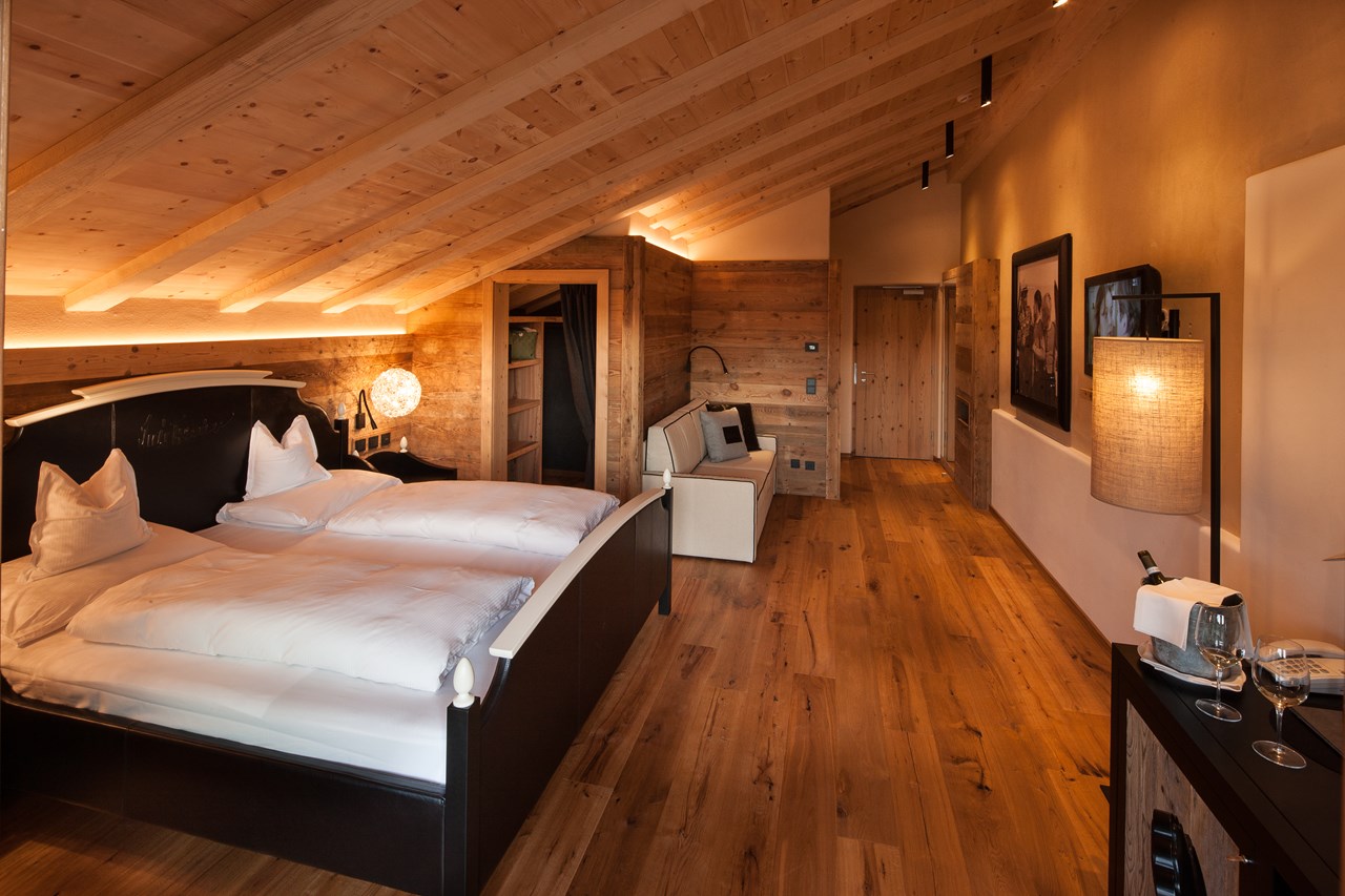 Tirler - Dolomites Living Hotel Zimmerkategorien Vertraut, komfortabel, heimelig und das alles im Zeichen einer Bergsteigerlegende Deluxe-Zimmer – 40 m² Luis Trenker