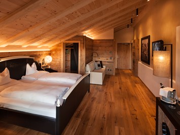 Tirler - Dolomites Living Hotel Zimmerkategorien Vertraut, komfortabel, heimelig und das alles im Zeichen einer Bergsteigerlegende Deluxe-Zimmer – 40 m² Luis Trenker
